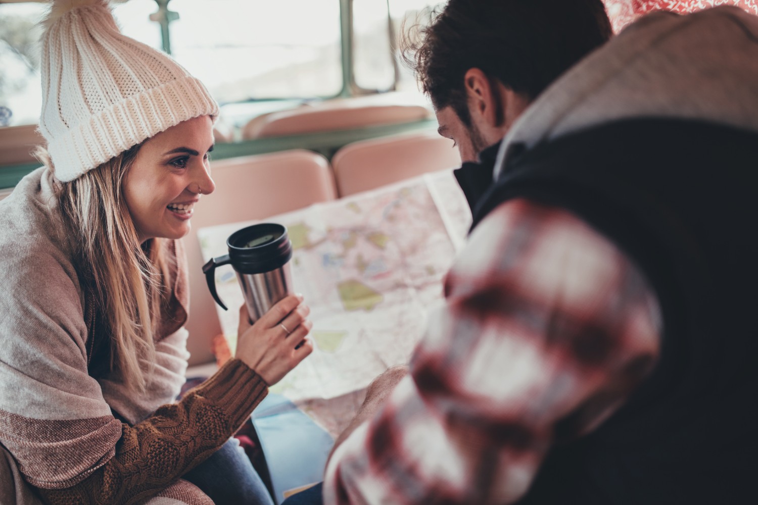 Couple planning a road trip with road map and thermos coffee