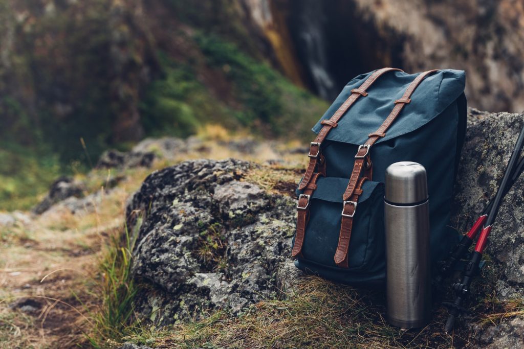 Hipster Blue Backpack, Thermos And Trekking Poles Closeup, Front View. Tourist Traveler Bag On Rocks Background. Adventure Hiking Outdoor | Hiking base in Oregon