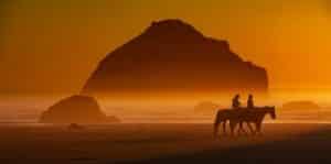 Oregon Getaways for Couples, photo of a couple horseback riding on the beach