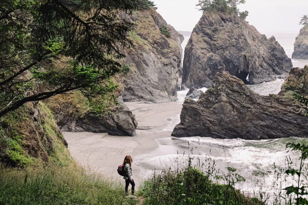 Woman standing with a view to a secret beach on Oregon coast. A lovely activity on your Oregon Coast Vacation